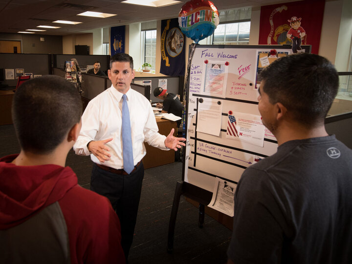 MVSC office with the executive directory speaking to two others near an event board and patriotic decor.