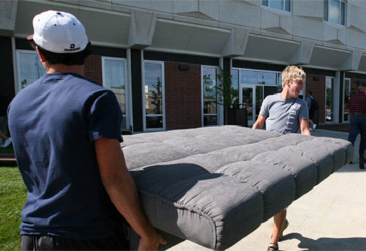 students moving a mattress into the dorms